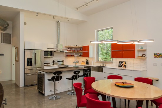 Bright red elements enliven the minimalist kitchen/dining area.