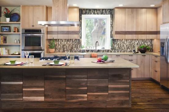 Clad in walnut cabinetry, contrasted by a limestone countertop, this island offers enough room for both cooking and casual dining. Variances in the wood are echoed in the pixilated glass tile backsplash, offering a cohesive design of equal parts rustic and modern. Project: Brykerwood Kitchen, Austin, Texas; Builder/Architect: CG&S Design-Build, Austin.