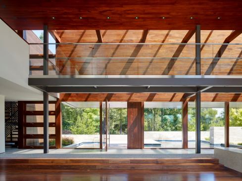 Grand, Custom Home 8,001 to 12,000 square feet. Builder: Lencioni Construction. Architect: Swatt | Miers Architects. The two-story great room, paneled in African mahogany, a contrast to the white stucco wings, serves as the center of the home with access to an expansive outdoor space accented with a pool.