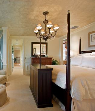 WELL PROPORTIONED: The master suite isn’t palatial by any means, nor does it need to be. Not when you’ve got a retractable Best Buy flat screen TV that folds neatly into a console at the foot of the bed. Also for your viewing pleasure: a panoramic view of nature beyond the rails of your own private balcony. A decorative Armstrong ceiling bears the look of hammered tin.