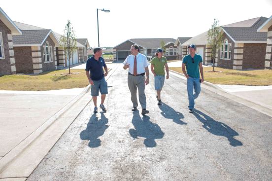Left to right: Tom Mayberry, Freeman Hospital Chaplain Todd Decker, Jason Mayberry, and Jake Mayberry walk in a neighborhood of rebuilt homes. Todd Decker survived the tornado in a home built by the Mayberrys, which was destroyed by the storm. Decker walked for hours to his job at Freeman Hospital, tending to the spiritual needs of an overwhelming crush of injured and dying patients.