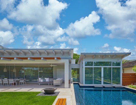 The kid’s bedroom wing appears to float and is capped by a butterfly roof and connected to the main volume by a glass link, surrounded by water on both sides.