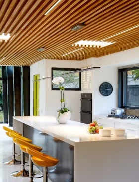 High gloss white cabinetry with a white quartz work island with waterfall edges make the kitchen a fresh interstitial space.