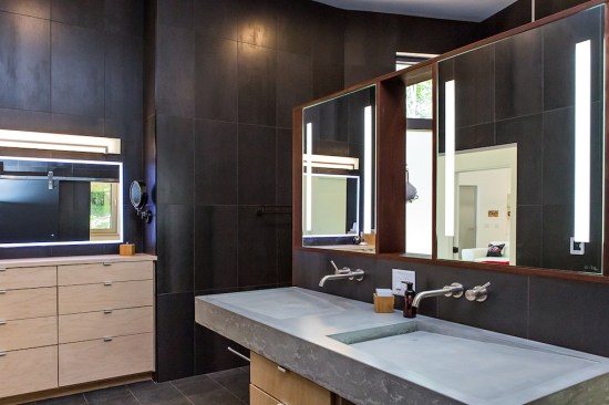 Floor and walls are covered in large-scale black tile in the master bath.