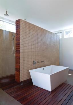 A tile-lined floating partition defines the bath's walk-in shower.
