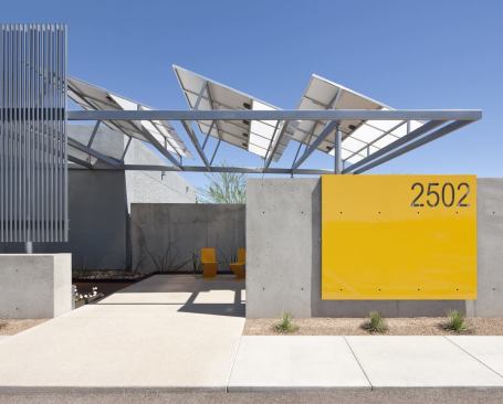 The renovated building entry boasts a new shade structure and solar panels.