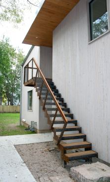 The second-floor rental unit is accessed by a steel and wood staircase that’s covered by a wood-clad canopy.