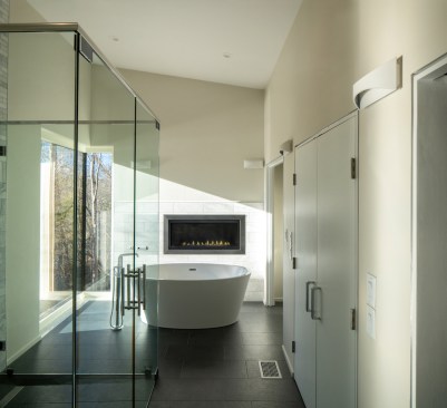 Green and luxe: The master bath features marble tile, a soaking tub, Passive-house-rated corner windows, and a fireplace.