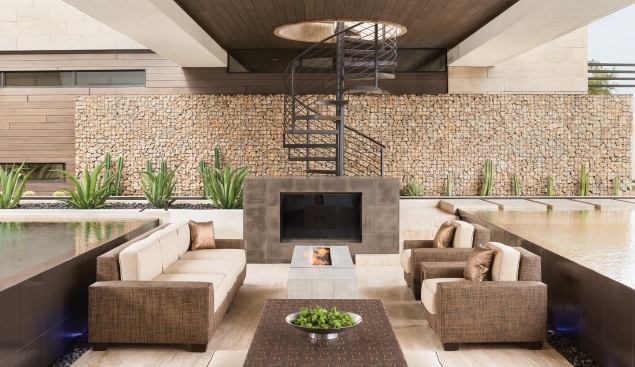 his area offers views into the great room and kitchen, while a spiral stair behind the TV niche leads to an open-air balcony above.