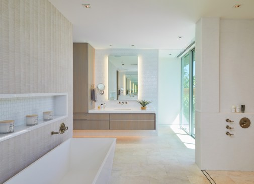 Clean lines and lots of natural light create an open, welcoming master bathroom, with separate his and hers vanities. Double sets of glass doors provide access to a private garden.