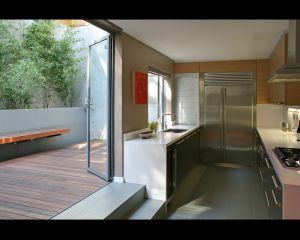 The kitchen in this four-story residence is on the second floor. It opens onto a secluded outdoor space carved into the hillside in back. Architect: Strachan Forgan Builder: Bradford Construction
