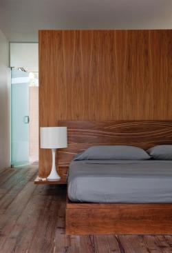 Standing a couple of feet shy of the ceiling, the millwork box presents a flush surface to the bedroom, where it serves as a headboard.