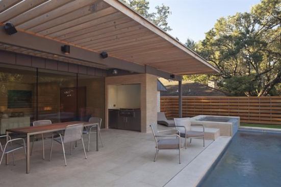 Materials used inside can extend to the exteior, forging inside-out connections. Here, the pool patio is shaded by a generous overhang.The grill is built into an alcove, near a fridge and prep space. 
Project: Chimney Corners, Austin, Texas; Builder: Melde Specialty Construction, Horseshoe Bay, Texas; Architect: Webber + Studio, Austin