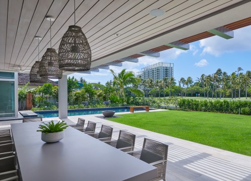 The main lanai features a custom all-weather dining table. A trellis mimics the Ipe rain-screens on the house and extends the shade.