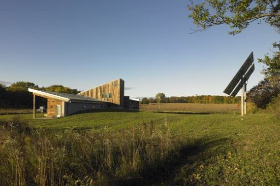 The building's main wing consists of a one-room-deep, single-story bar that lifts its rood to the south for passive solar gain. An earth berm on the north side shelters the building from heat loss and noise intrusion. The second, intersecting roof that pitches to the north creates a sleeping loft for visitors and provides a mounting surface for solar hot-water panels.