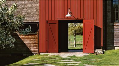 The dominant visual element of the arrival court at this Hudson Valley farmhouse is a barn-board-clad tower, which serves as an entry point and links the main wing of the house to the guest quarters. The entry under the tower is like a breezeway with big barn doors on each side.