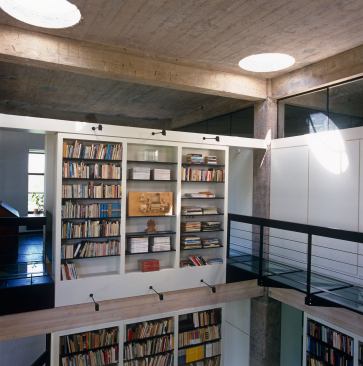 De Bretteville eventually added slender glass walkways that tie into the main balcony for easier access to upper shelves.