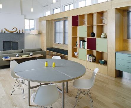 Cabinets of maple plywood and matte-colored laminate line the north wall, creating a visual tie between kitchen and living area.