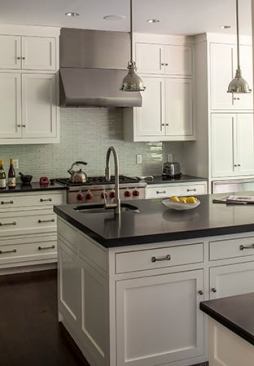 The redesigned kitchen features plumbing fittings by Rohl (rohlhome.com) and new custom cabinetry. It opens into a dining area sporting large windows.