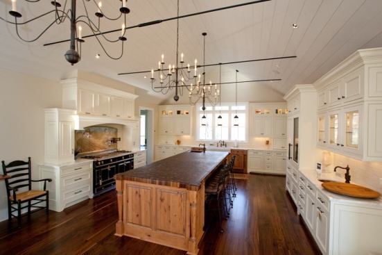 The kitchen is the ideal showcase for the house's sleek traditional style. Its milk-white cabinetry and light walls are balanced by the darker walnut flooring and the walnut butcher-block island countertop. A massive La Cornue range anchors the cooking side of the room, while the opposite side serves as the preparation and bar area. Aside from the range, all appliances are concealed behind cabinetry panels or stowed in the butler's pantry.