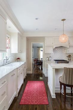 View past sink in beautiful white kitchen into dining room
