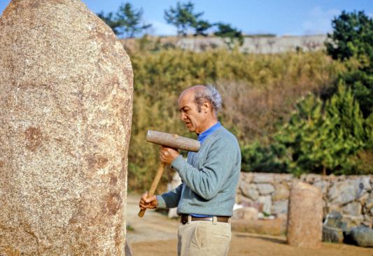 Noguchi working in stone yard at his Mure, Japan studio, 1975