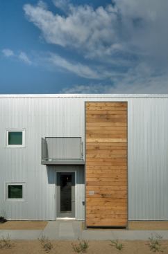 Reclaimed wood from the original 1923 Arizona Ice and Cold Storage building (here, converted to lofts) contrasts with the corrugated steel skin of the building, and gives shade from the western sun at the entry door. Location: Tucson, Ariz.; Architect: Rob Paulus