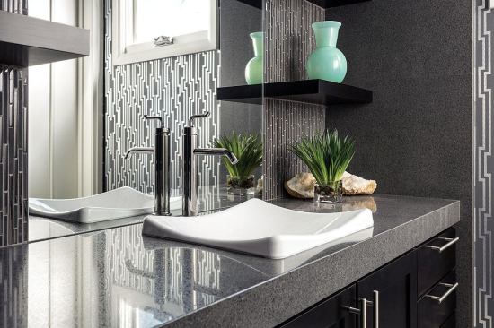 The carriage suite bathroom boasts luxe finishes including a striking Daltile backsplash, Kohler faucet and sink, and open shelving on either side of the quartz-surfaced vanity.