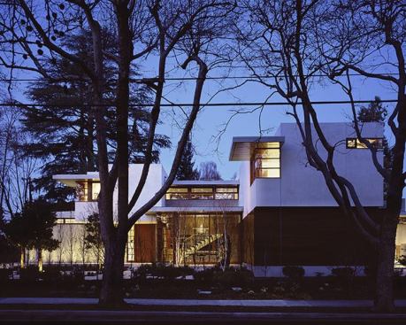 At night, the glassed-in dining room pavilion glows, letting passers-by view the central staircase in the background.