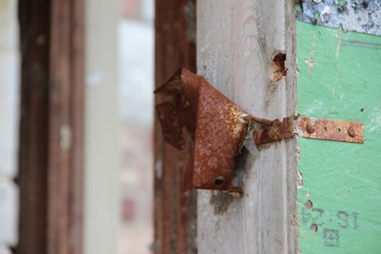 A rusted strap shows where the connection between a window unit and the rough opening failed during the storm. All the windows in this structure, a dentist office, were blown in during the tornado, making the interior space unsafe and likely unsurvivable. The office was closed on the Sunday evening when the storm struck.