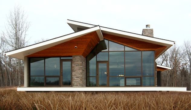 The stained cedar soffit for this home’s roof truss is a warm contrast to the glass façade, and its upturned shape makes the roof appear to float above the house. Location: West Plains, Missouri; Architect: Core10 Architecture