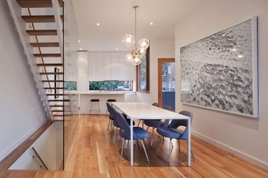 The main floor features an open kitchen with Caesarstone countertops and cabinets by Catfish Design/Build. The white oak flooring continues into the dining area and the living spaces upstairs.
