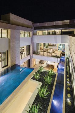 From the second-story balcony, accessed by the spiral stair, as well as an interior staircase that leads to a billiard lounge and bar overlooking the kitchen, all of the elements of the house come together and reveal its three main levels (the fourth level is a sky deck above the lounge).