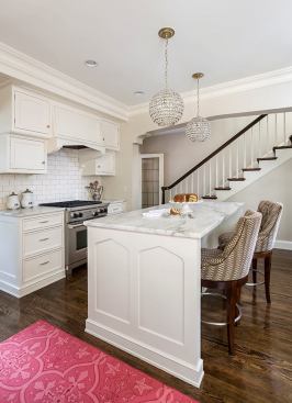 Stairway descends behind white kitchen and kitchen island