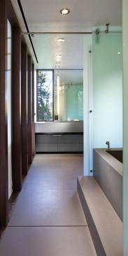 Engineered stone forms the floor, tub, and wainscot of this master bath, which doubles as a pool cabana. Sliding glass partitions at the tub yield a variety of possible configurations.