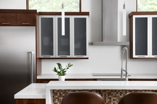The warm neutrals and textures of natural materials offer a connection to the natural site and create interest in a modern home. Privacy is preserved from neighboring homes in rising stone walls that give way to transom windows for natural light and tree canopy views. 
