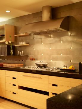 The cooktop area anchors the room, serving as a modern-day hearth. The vent, designed by Cheng, is a quarter of an ellipse; its graceful shape keeps the hood from overpowering the room.