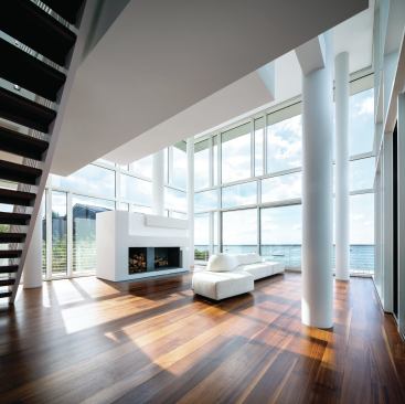 The double-height living room faces the water, and a large built-in fireplace helps ward off winter chill for a year-round experience.