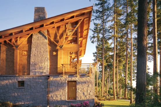 The soaring second floor of the house, clad in semi-transparentstained cedar shingles, sits atop the granitesheathed lower level.