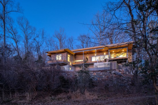 With its cantilevered porches and decks, the house appears to rest lightly on top of the bolder-filled knoll.
