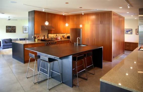 This kitchen claims its own space while remaining integrated with the open layout of this modern home thanks to a massive partition loaded with built-in cabinets and pantry. Project: Graham Street Residence, Raleigh, N.C.; Designer/Builder: Will Alphin, Alphin Design Build, Raleigh