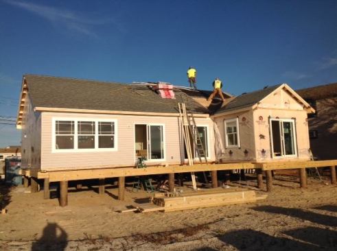 Workers secure the house to its foundation or pilings and add the porch.