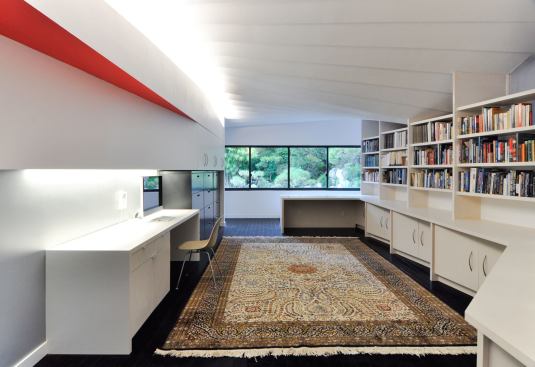 Architect David Freeland wanted the client's law books and photography to be artfully displayed as well as neatly stored. He used canted shelves and an angled ceiling to provide interest in the monochromatic space.