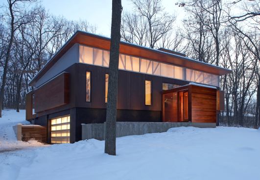 A radical renovation, the Ferrous House by Johnsen Schmaling Architects reinvents an obsolete suburban production home with a resource-conscious replacement designed for contemporary lifestyles. The building's exterior is clad in weathering steel panels that offer a dark, rough contrast to the light-suffused, aerogel-filled polycarbonate clerestory glazing and tall slits of clear, energy-efficient windows.