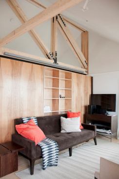 The home’s living room features a movable storage wall and exposed framing.