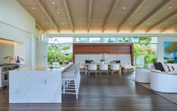 The entry area Ipe rain-screen turns into the great room to frame a casual built-in seating area surrounded by windows, which emphasizes the indoor-outdoor relationship on both sides of the house.