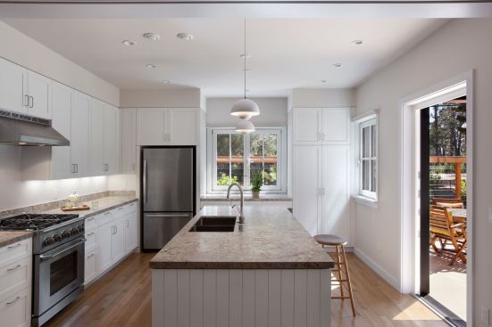 The kitchen opens directly onto a stone terrace, which is secluded behind a natural wood fence and is adjacent to the front entry as well.