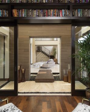 From the library, a sequence of living spaces is framed by wide passageways and contrasting yet complementary materials, emphasizing the home’s design and giving it a human scale.