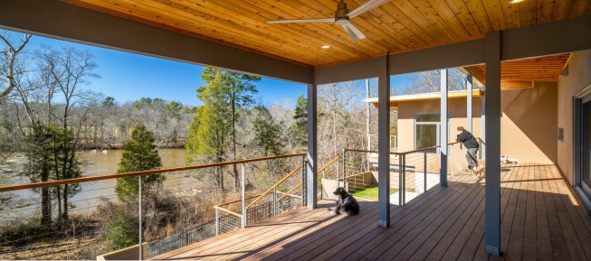 The homeowners enjoy the view of the frothy river from the covered porch.