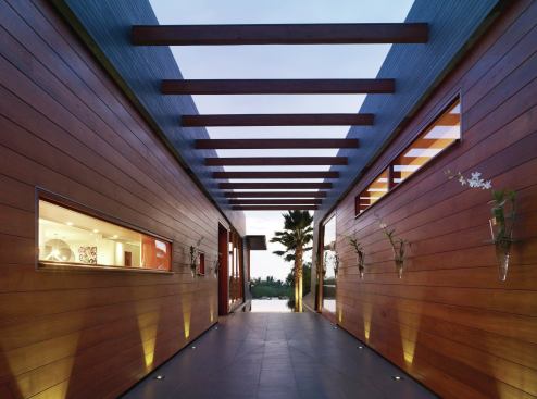 Recycled teak timbers join two pavilions across the entry corridor.  